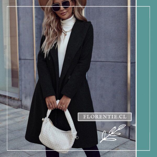 Modelo con abrigo negro elegante entallado, sombrero y bolso blanco en look casual chic de invierno.