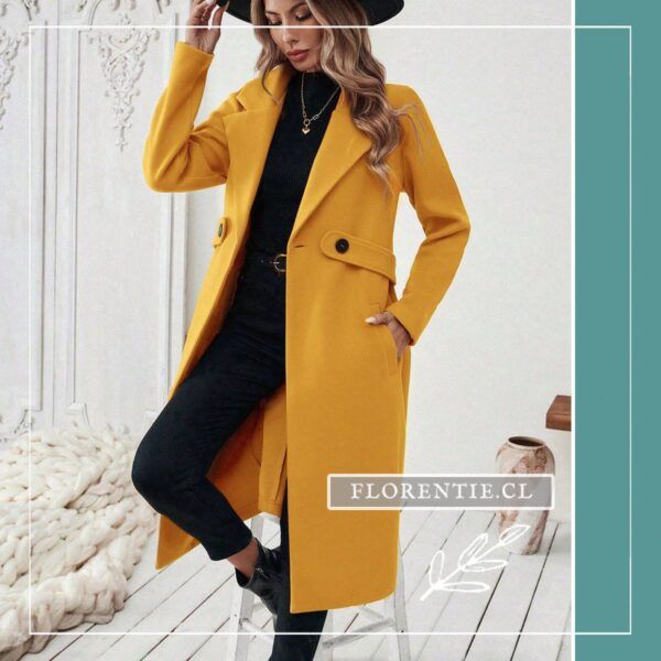 Modelo con sombrero negro luciendo abrigo color amarillo mujer de largo hasta la pantorrilla, botas negras y look sastre
