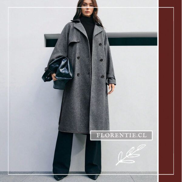 Modelo de cuerpo entero con abrigo largo gris oscuro sin cinturón, cuello polera negro, pantalón palazzo y bolso de cuero oscuro en exterior minimalista.
