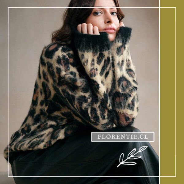 Modelo sentada con sweater leopardo afelpado y cuello beatle negro doblado, look invernal con pantalón oscuro.