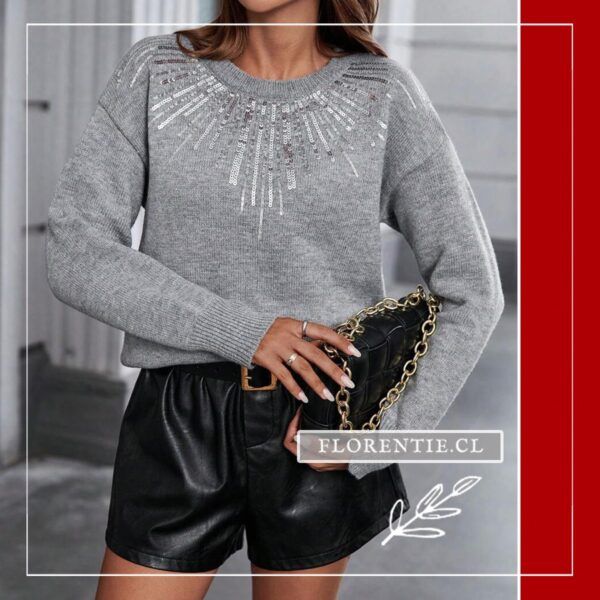Plano medio del chaleco gris con patrón radial de lentejuelas plateadas en escote redondo, modelo sosteniendo bolso negro de cadena dorada sobre shorts de ecocuero negro.