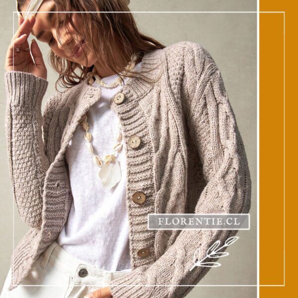Modelo con cárdigan abotonado beige avena con trenzas y botonadura frontal grande, combinado con collar artesanal y camiseta blanca.