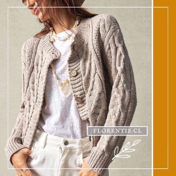 Modelo luciendo cárdigan abotonado mujer beige de punto grueso con trenzas, abierto sobre camiseta blanca y jeans blancos.