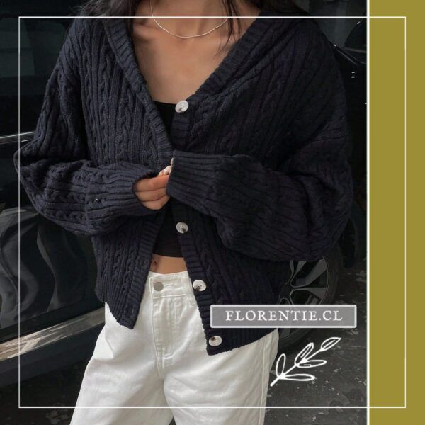 Vista media del cardigan azul marino abotonado con trenzas verticales, capucha y botones nacarados, sobre pantalón blanco, look exterior urbano.