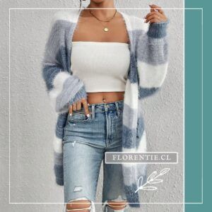 Mujer usando cardigan oversize de franjas azules y blancas con tejido peludo, combinado con top blanco bandeau y jeans rotos, mano en bolsillo