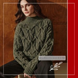 Modelo sentada luciendo el chaleco verde oliva de trenzas gruesas con cuello alto, combinado con pantalón ancho negro.