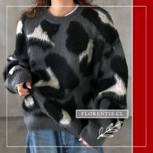 Modelo de frente con sweater oversize animal print gris y negro sobre camiseta blanca y jeans claros, mano en bajo de la prenda.