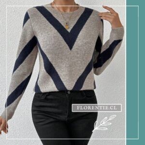 Modelo de frente con sweater gris de patrón chevron azul marino, collar dorado delicado, combinado con jeans negros de tiro alto sobre fondo blanco texturado.