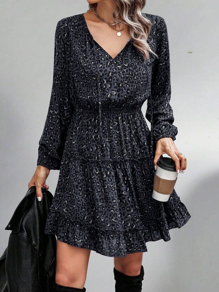 Modelo con vestido animal print gris oscuro escote en V, manga larga abullonada y falda con volantes, sosteniendo café y chaqueta negra