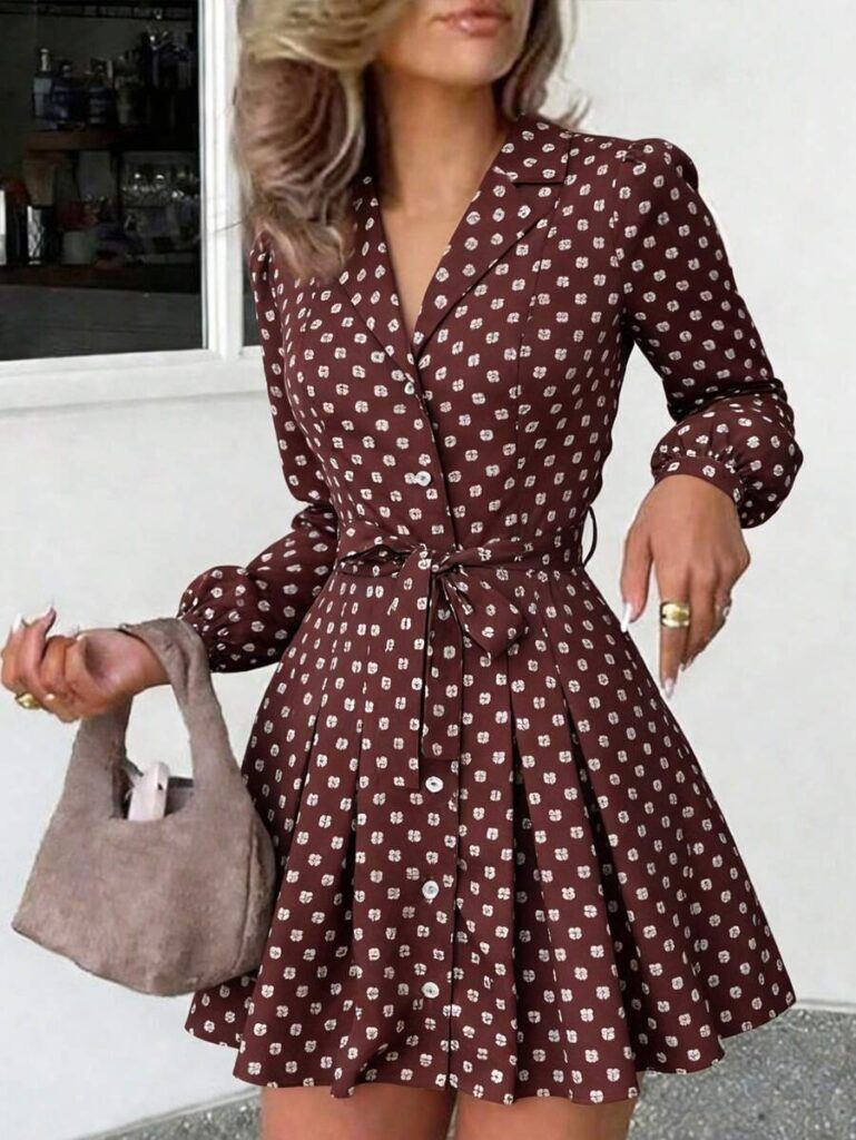 Modelo luciendo vestido camisero café con lunares blancos, cuello solapa, cinturón anudado en cintura y falda plisada con vuelo, sosteniendo bolso beige