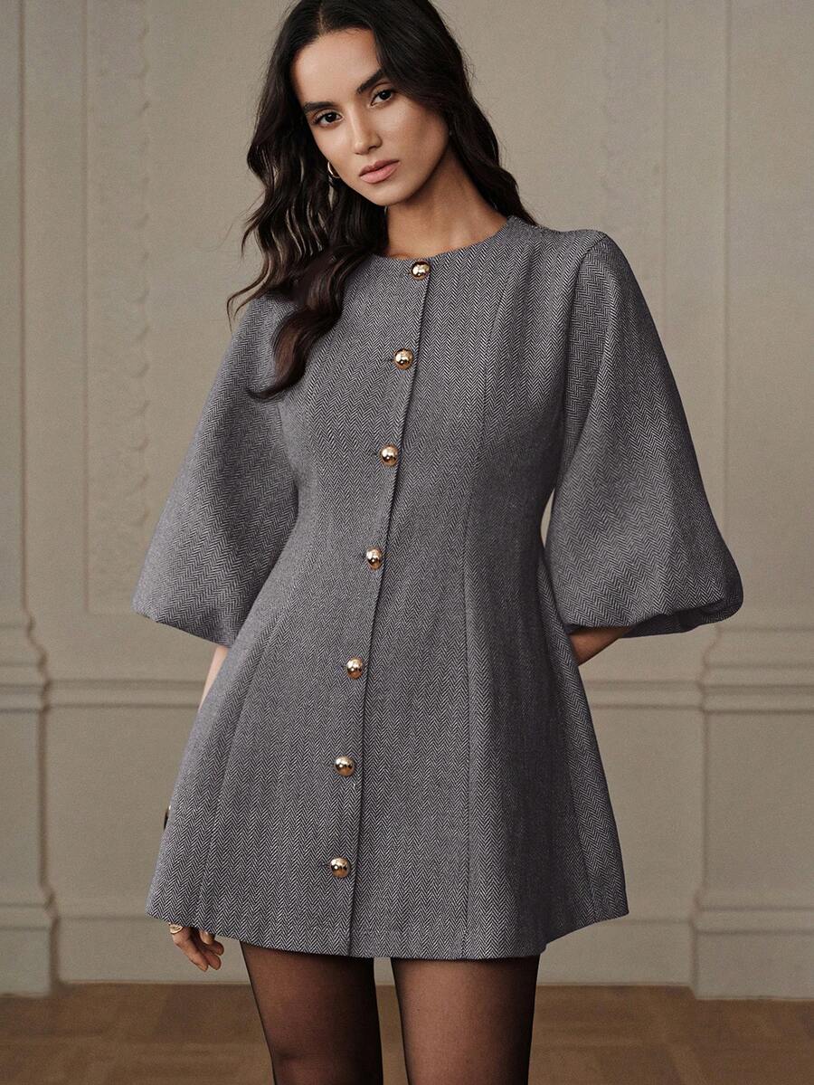 Modelo con vestido corto gris tejido espiga con manga campana y botones dorados esféricos, pose frontal con fondo elegante beige
