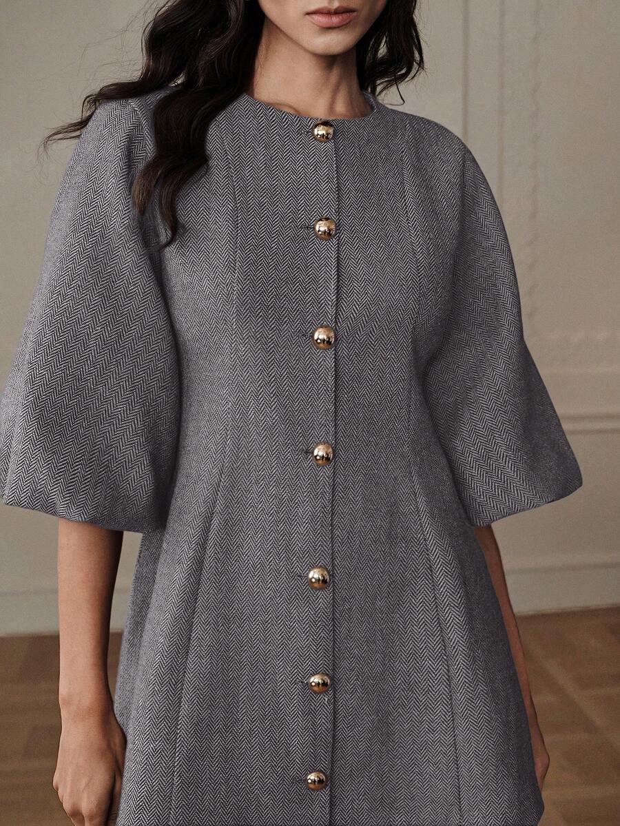 Detalle del torso mostrando tejido espiga gris y línea de botones dorados esféricos en vestido manga campana invierno