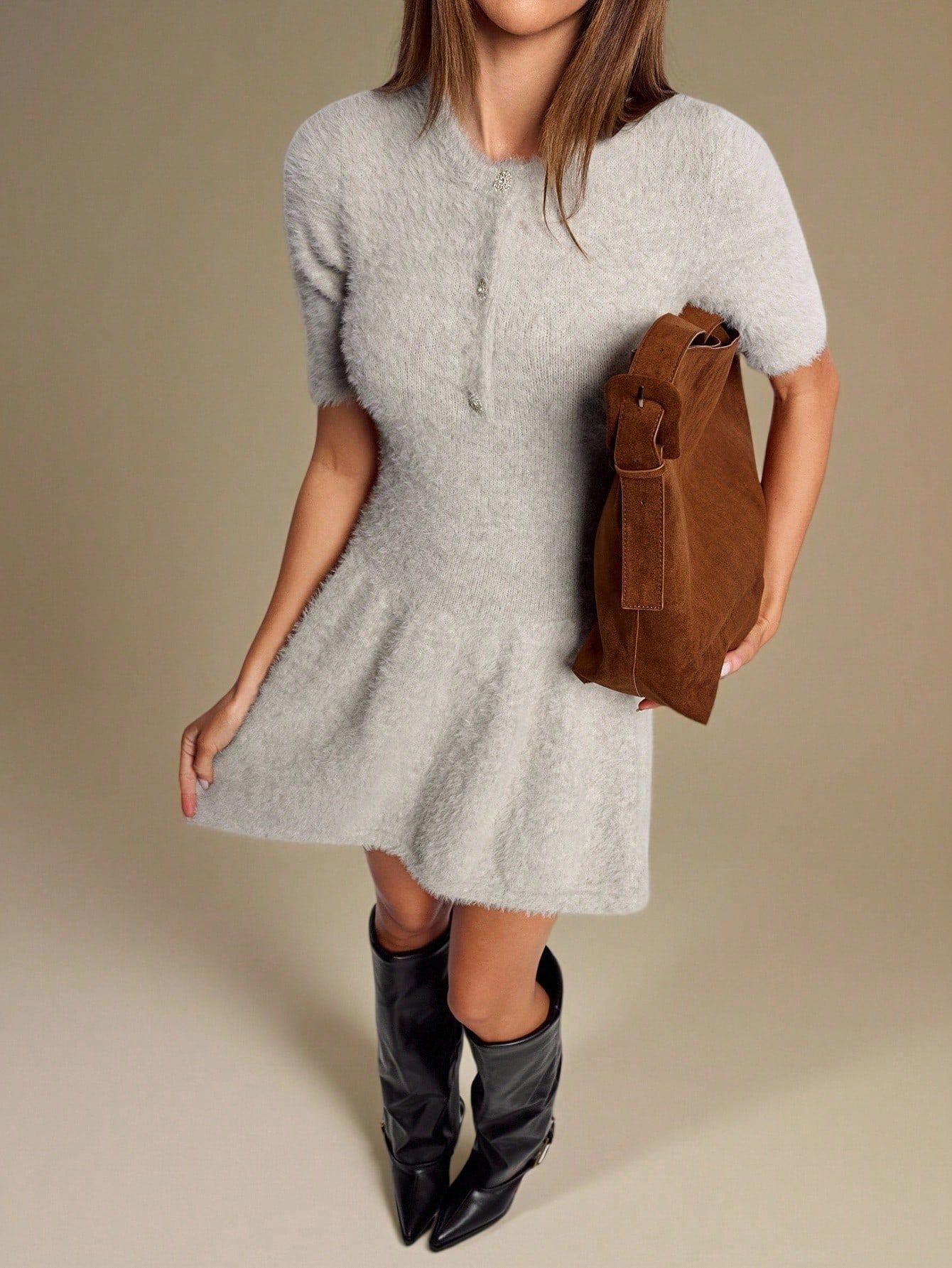 Modelo con vestido gris de tejido suave sosteniendo bolso café, combinado con botas negras de cuero hasta la rodilla