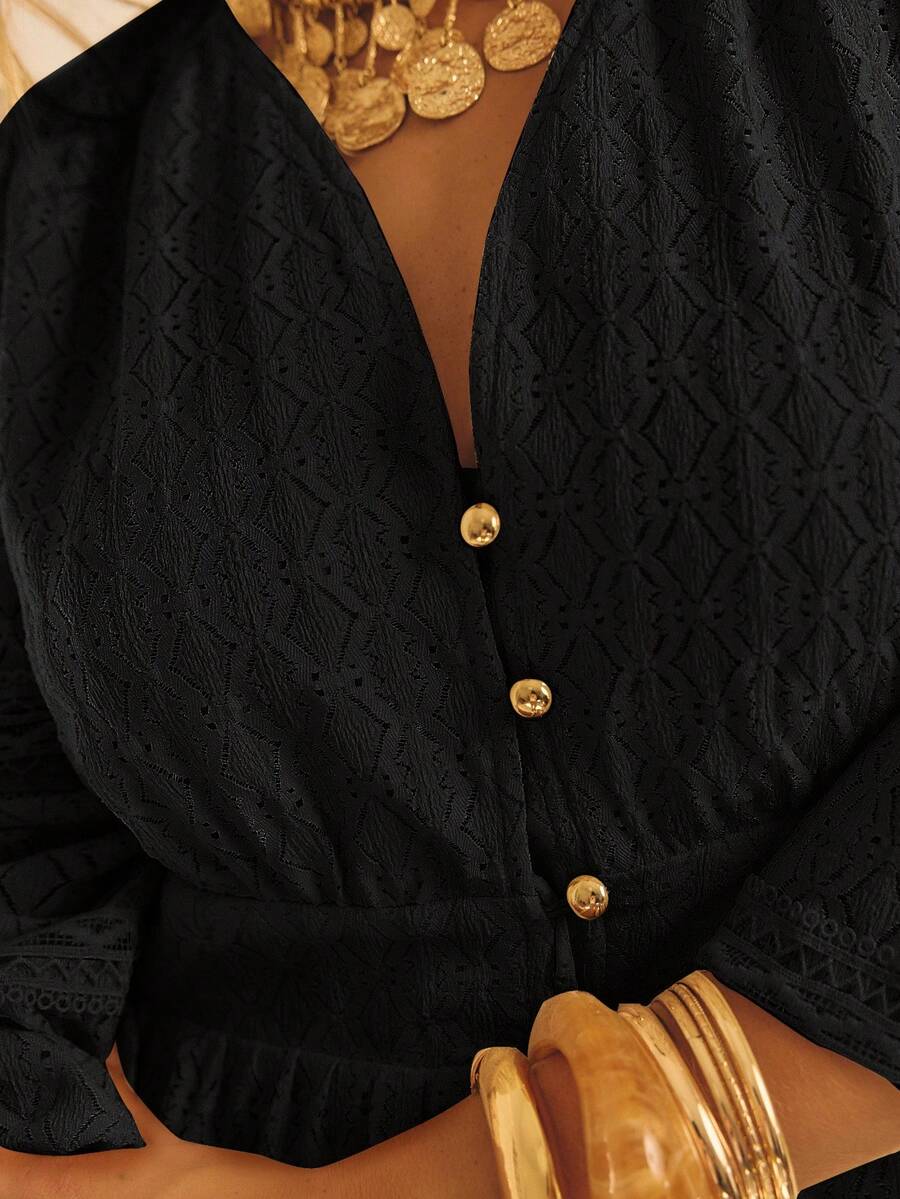 Acercamiento al escote en V del vestido negro con tejido de rombos, tres botones dorados visibles, manga abullonada y collar de monedas doradas como complemento