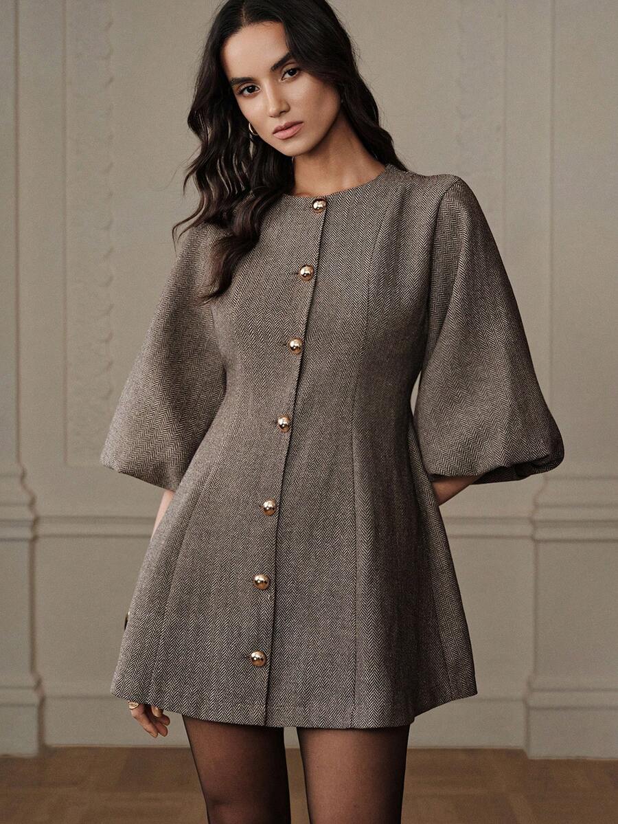 Modelo con vestido corto de tweed espigado café con botones dorados, manga campana tres cuartos, pose frontal elegante con fondo clásico