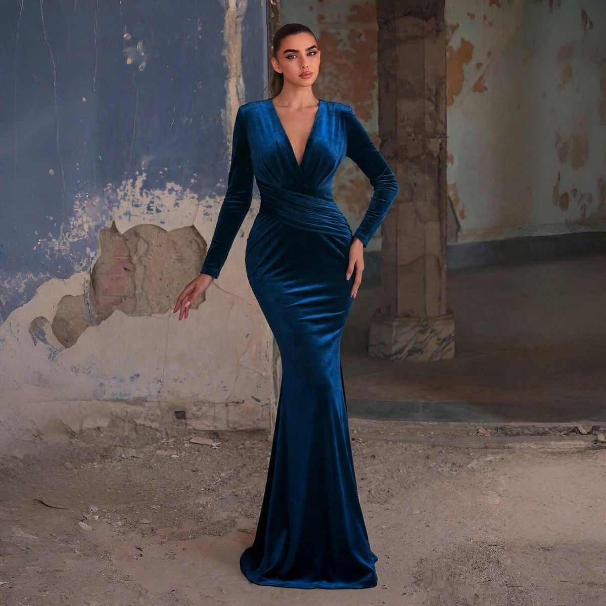 Vestido gala corte sirena en terciopelo azul petróleo con escote V cruzado, manga larga ajustada y drapeado diagonal en cintura