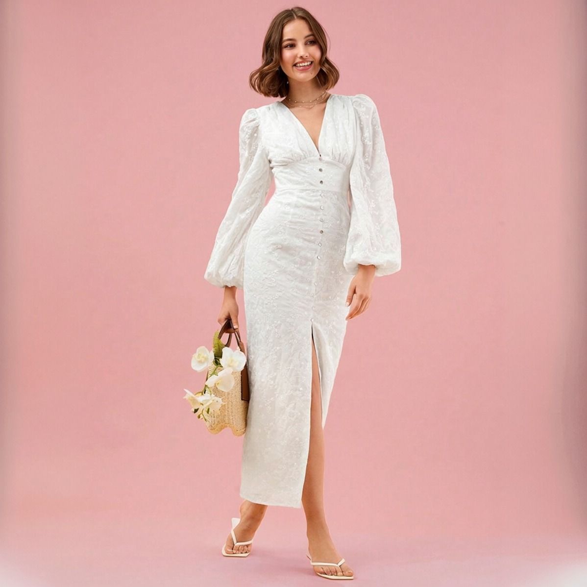 Vestido midi blanco con botonadura frontal y abertura inferior, modelo caminando con bolso de mimbre
