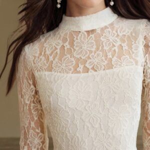 Detalle del cuello alto fruncido y encaje floral blanco con transparencia en hombros y mangas del vestido midi