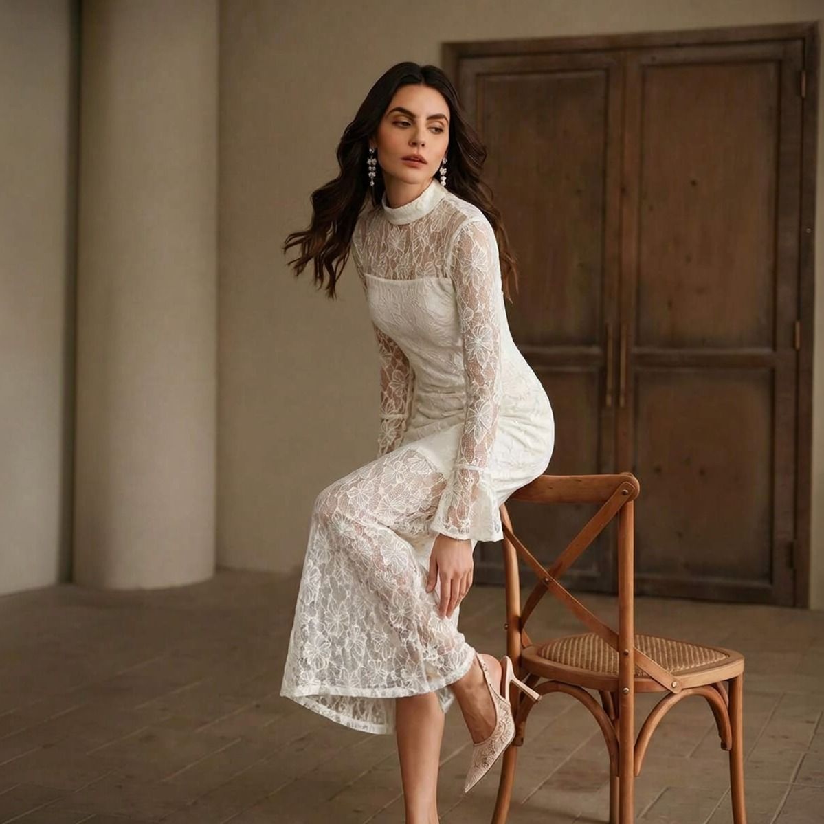 Modelo sentada con vestido midi de encaje floral blanco mostrando la caída del ruedo transparente y puños campana