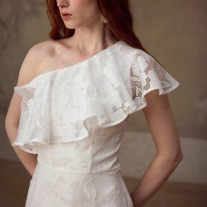 Detalle del corpiño con volante de encaje floral y escote un hombro del vestido blanco Amapole