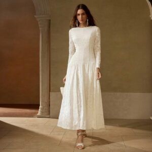 Vestido blanco marfil en encaje floral con manga larga y falda evasé maxi visto de frente sobre fondo neutro