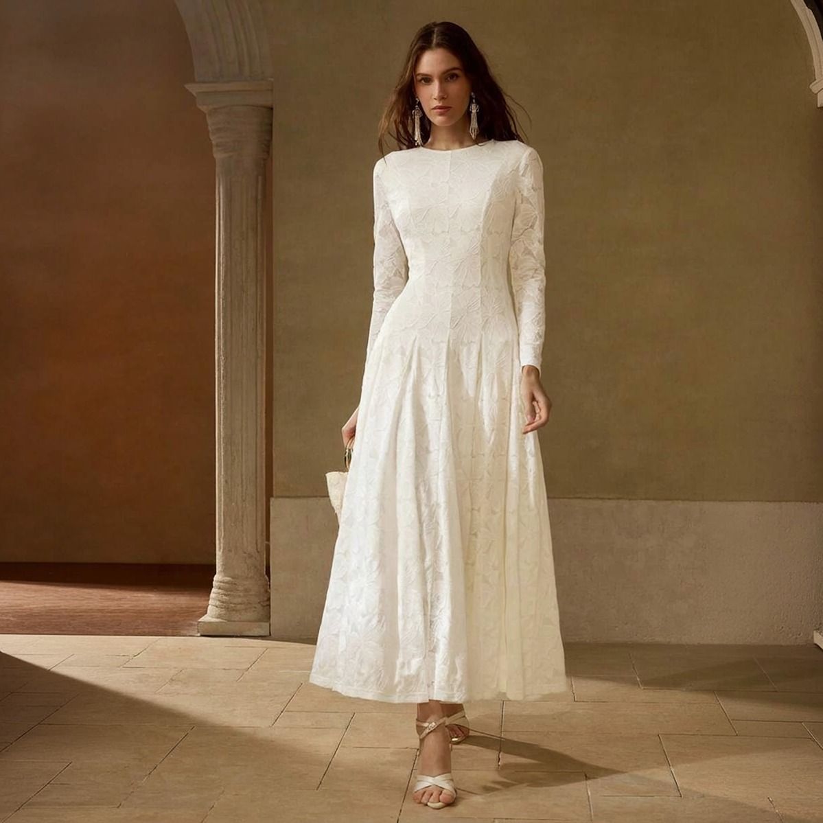 Vestido blanco marfil en encaje floral con manga larga y falda evasé maxi visto de frente sobre fondo neutro