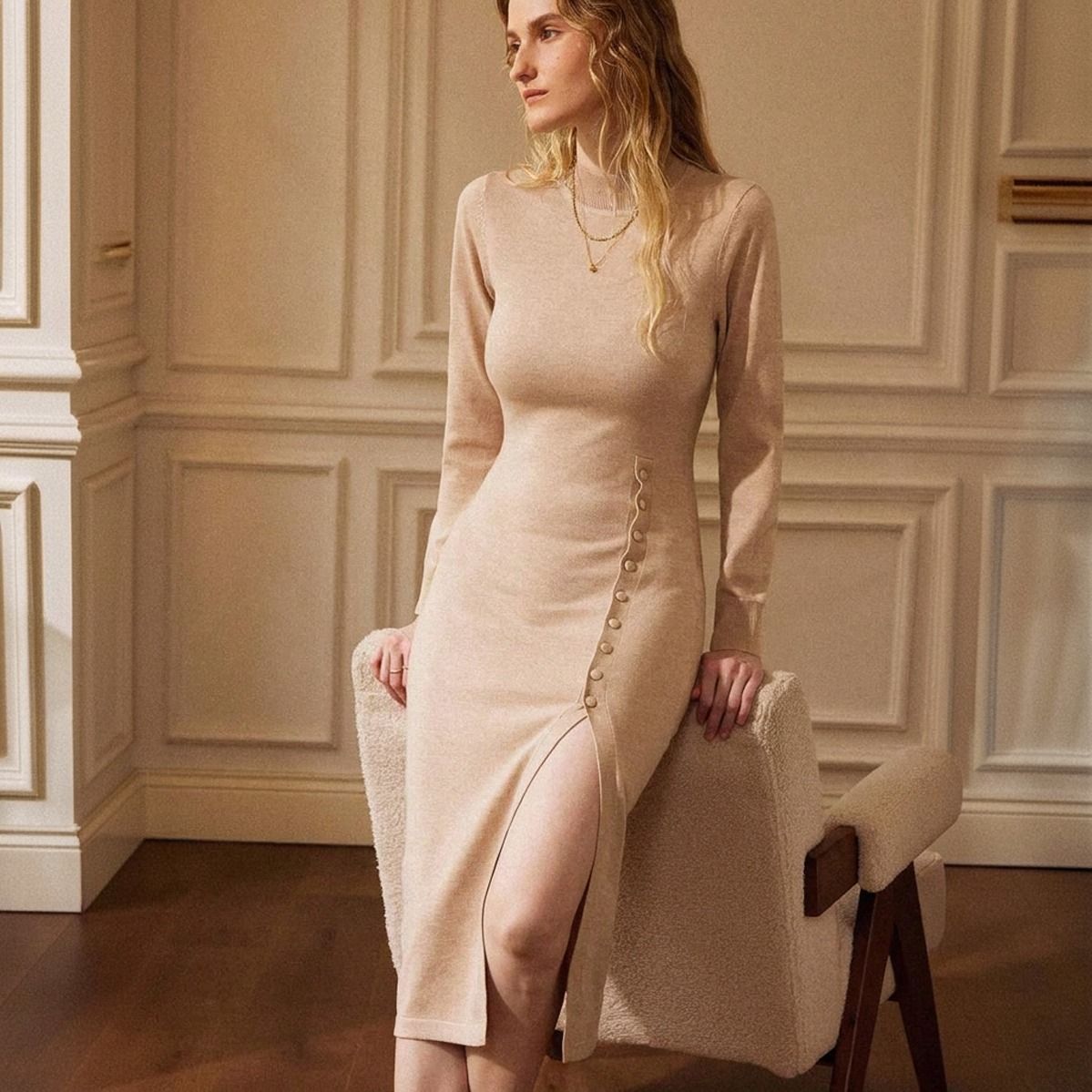 Vestido de punto beige entallado visto de frente, manga larga, cuello alto y abertura lateral con botones