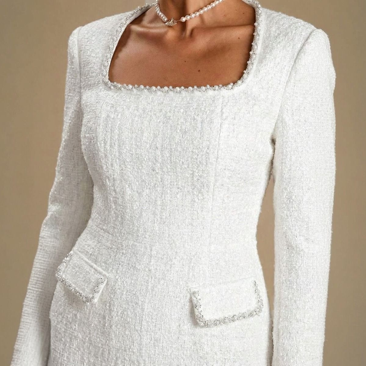 Detalle del escote cuadrado con ribete deshilachado y bolsillos con solapa en vestido de tweed blanco