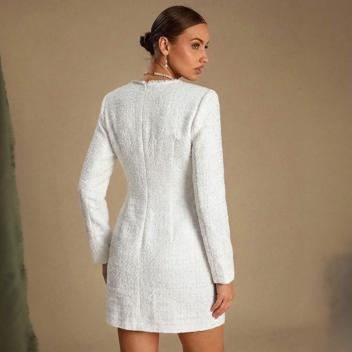 Vista posterior de vestido corto de tweed blanco con cierre oculto central y costuras de entalle en la espalda