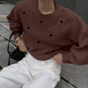 Sweater tejido chocolate con corazones negros bordados visto de frente en plano medio sentado