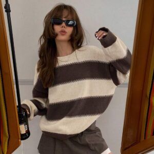 Sweater oversize beige con franjas café chocolate visto de frente sobre modelo con minifalda gris