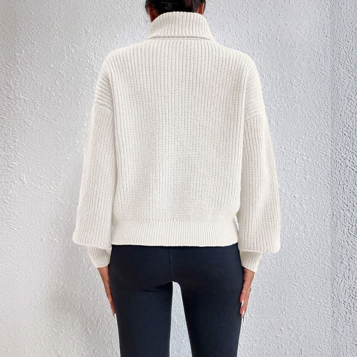 Vista trasera de sweater cuello tortuga crudo mostrando silueta oversize con banda acanalada inferior y mangas amplias