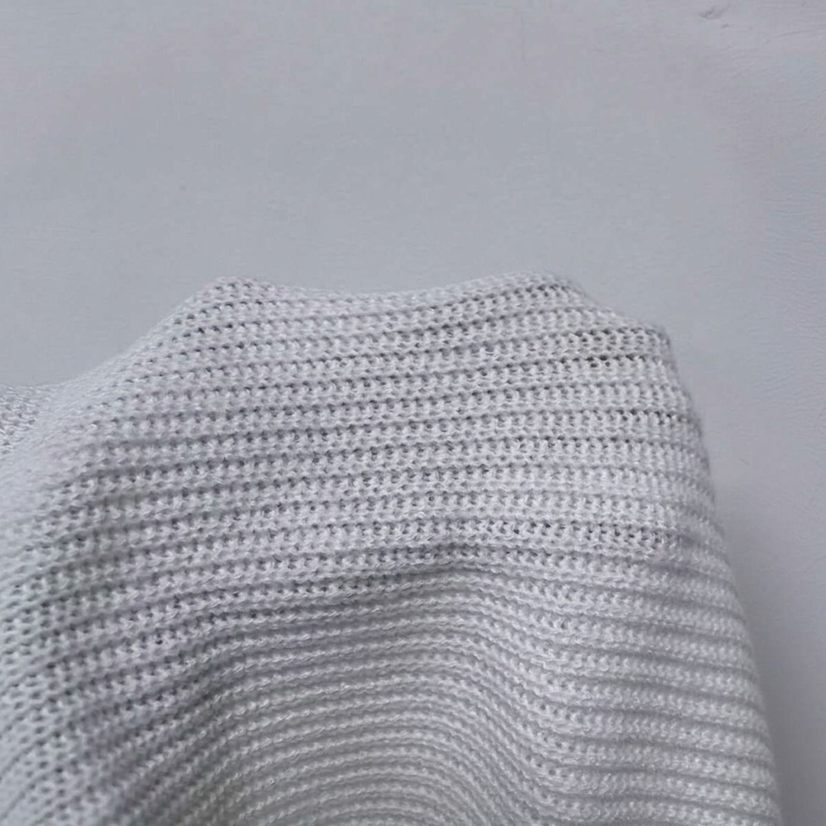 Detalle macro del tejido de punto acanalado grueso en color crudo del sweater cuello tortuga Murcielago