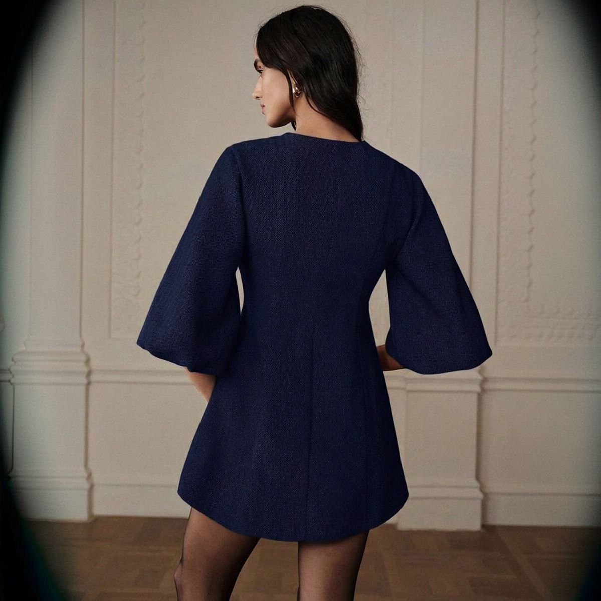 Vista trasera del vestido corto azul marino en tweed mostrando espalda lisa con costura central y mangas abullonadas
