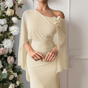 Detalle frontal del vestido beige con capa de gasa, hombro descubierto y flor de tela aplicada sobre el hombro