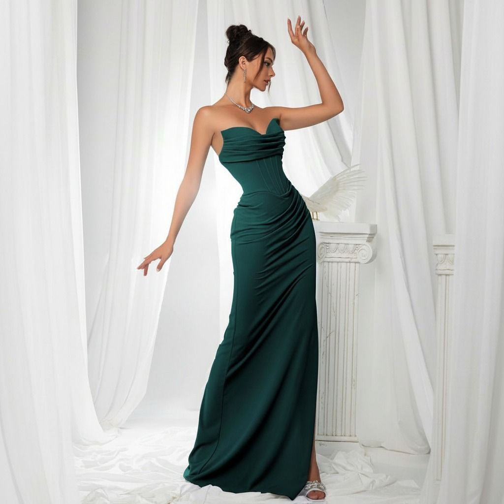 Modelo de perfil con vestido largo verde esmeralda strapless, cuerpo corset drapeado y falda ajustada