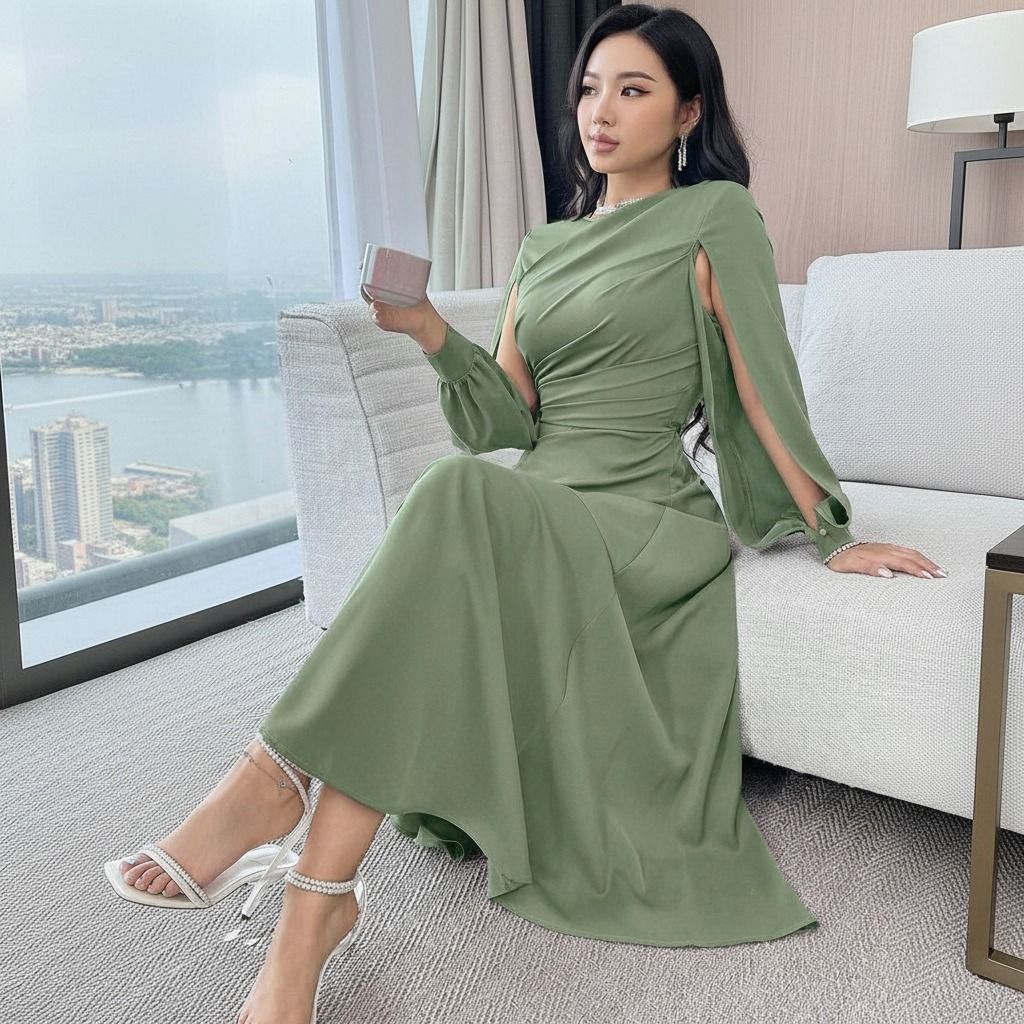 Modelo sentada con vestido midi verde salvia mostrando la caída de la falda evasé y manga capa abierta