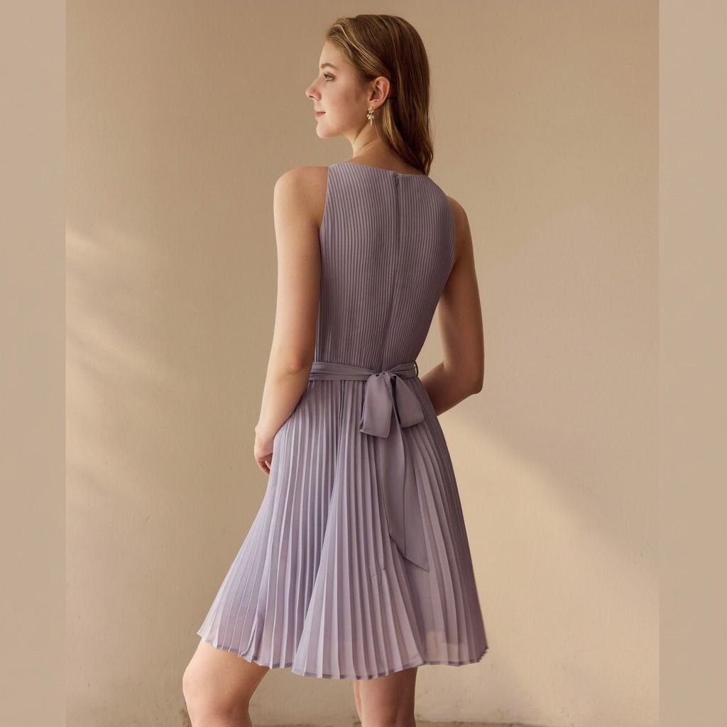 Vista trasera del vestido lila plisado con lazo en la espalda y falda evasé sobre la rodilla