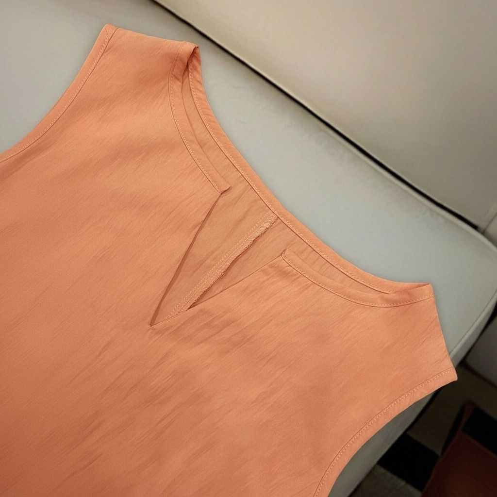 Detalle del escote notch en forma de muesca en V del vestido melocotón con costuras limpias en la sisa