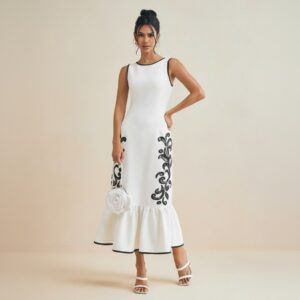 Vestido midi blanco sin mangas con bordados negros en la falda y volante inferior, vista frontal completa