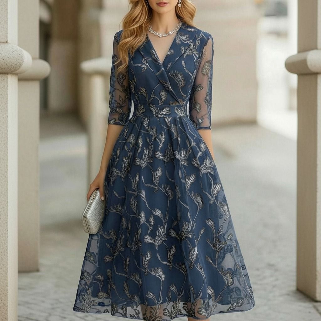 Vestido midi azul acero con bordado floral plateado, escote cruzado con solapa y mangas 3/4 de tul, vista frontal completa