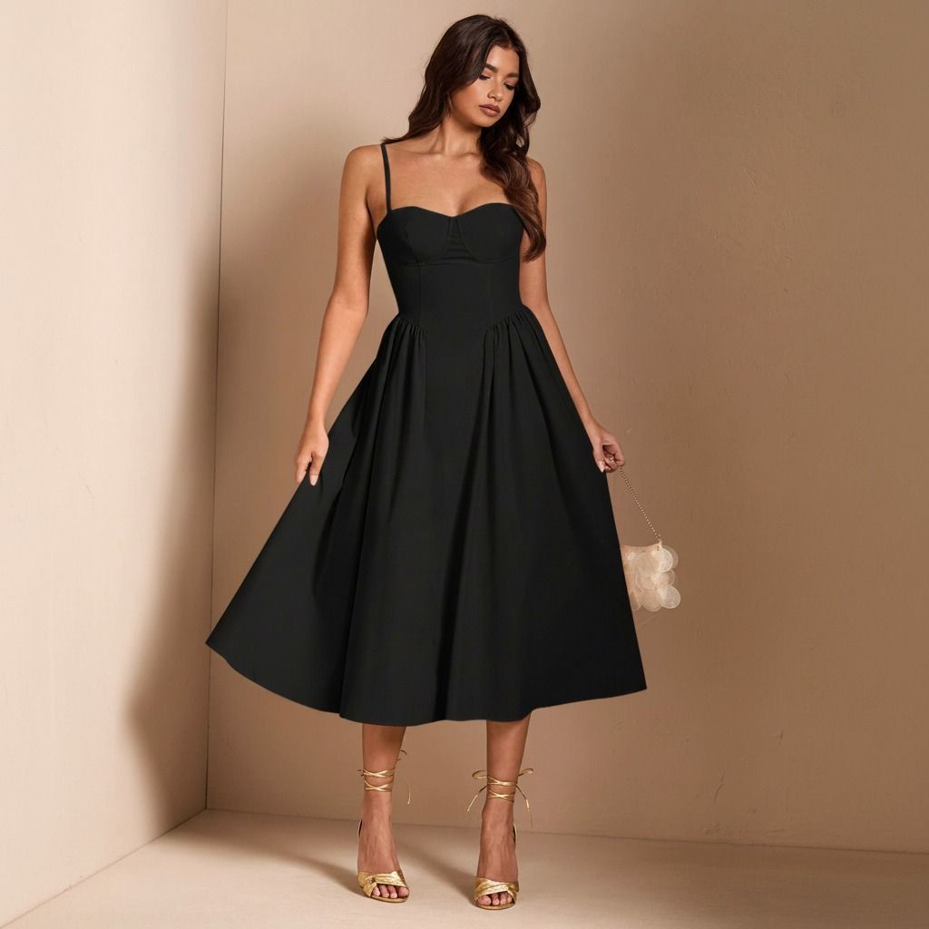 Detalle de pliegues desde la cintura en vestido midi negro con cuerpo corsé y falda amplia evasé