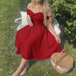 Mujer sentada en jardín usando vestido midi rojo con escote off-shoulder y lazo frontal, falda evasé