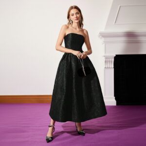 Vestido strapless negro en jacquard floral con silueta A-line y largo midi visto de frente con clutch negro
